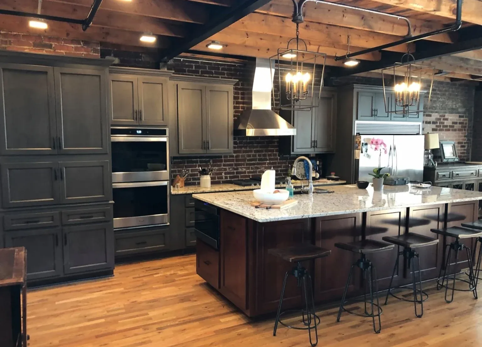 Warm kitchen with timber beams, dark fitted cabinetry and a substantial wood island